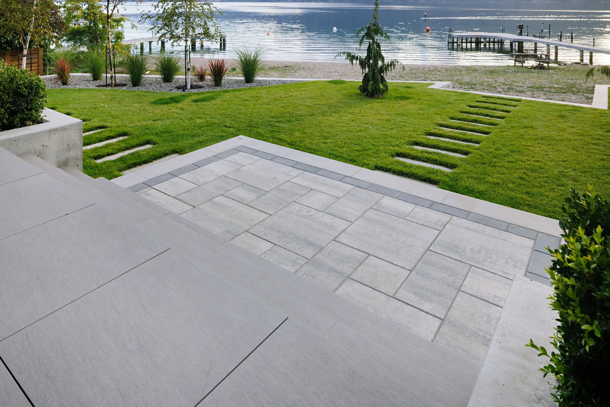 retaining wall and stairs with a paver stone walkway and green lush grass